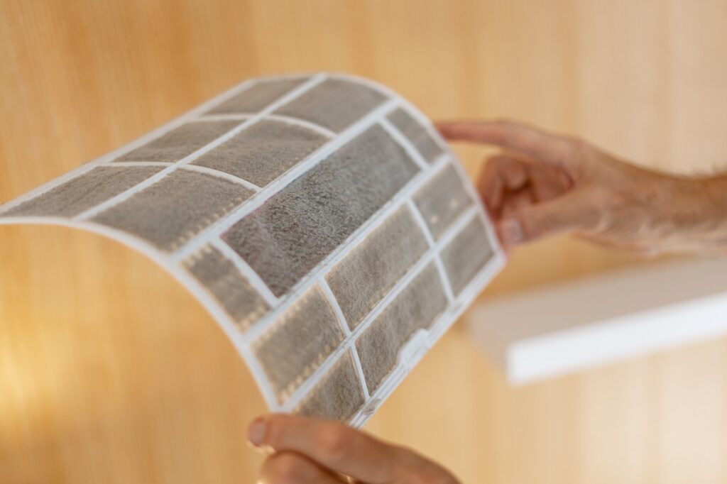 Serviceman holding air conditioner filter, replacement, cleaning in apartment closeup