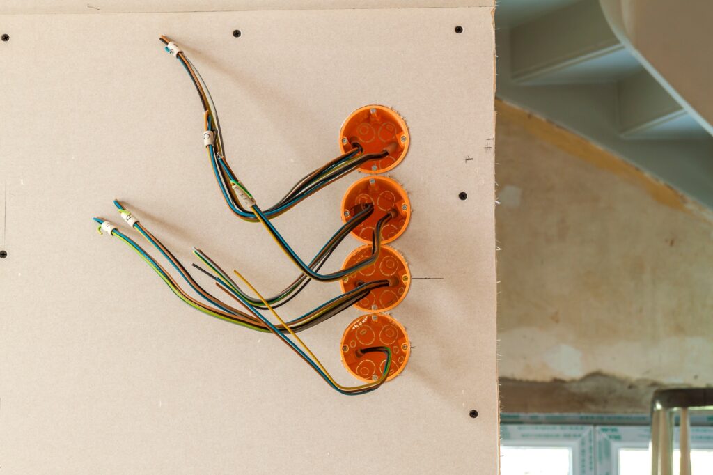 New electrical installation, socket plastic boxes and electrical cables on the wall, renovation